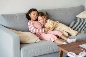 Sisters hugging on the sofa and laughing